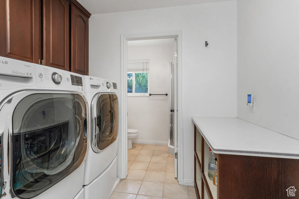 Laundry area with cabinet space, washing machine and clothes dryer, and light tile patterned floors