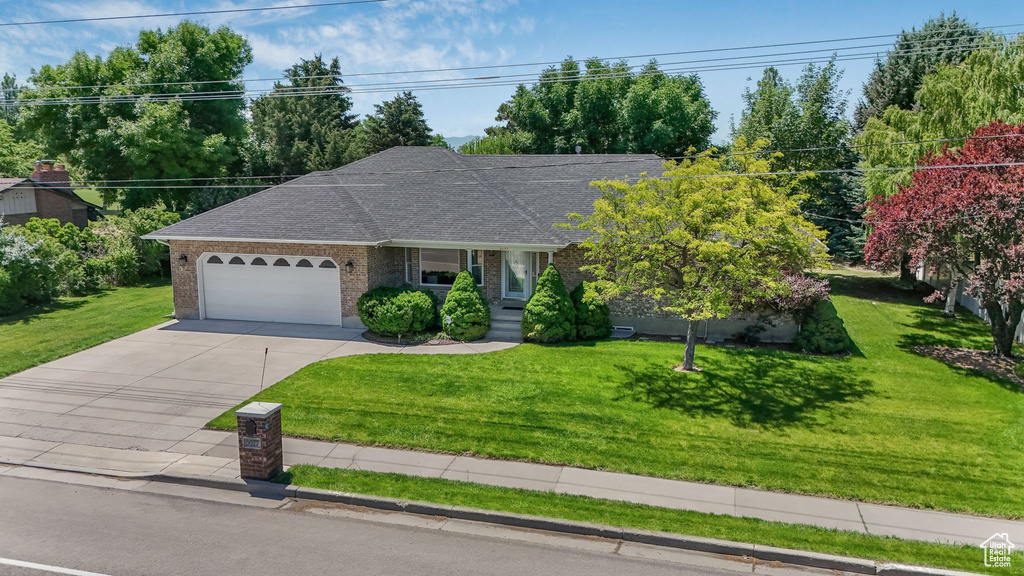 Single story home with a garage, concrete driveway, and a front yard