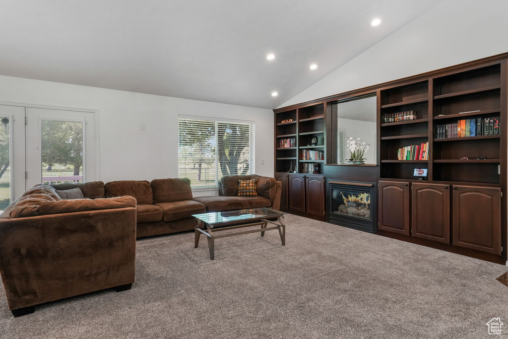 Carpeted living area with plenty of natural light, a glass covered fireplace, recessed lighting, and vaulted ceiling