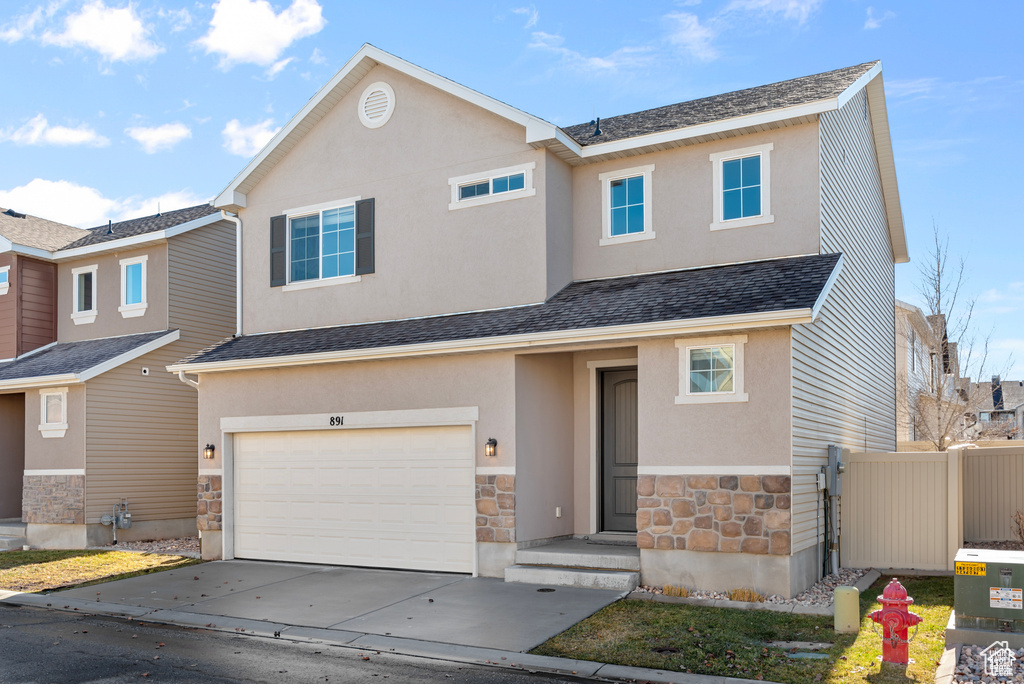 View of property with stone siding, a garage, driveway, stucco siding, and a shingled roof