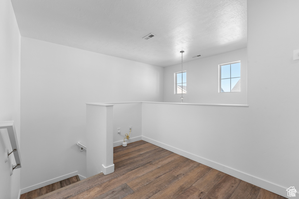 Laundry room with wood finished floors and a textured ceiling