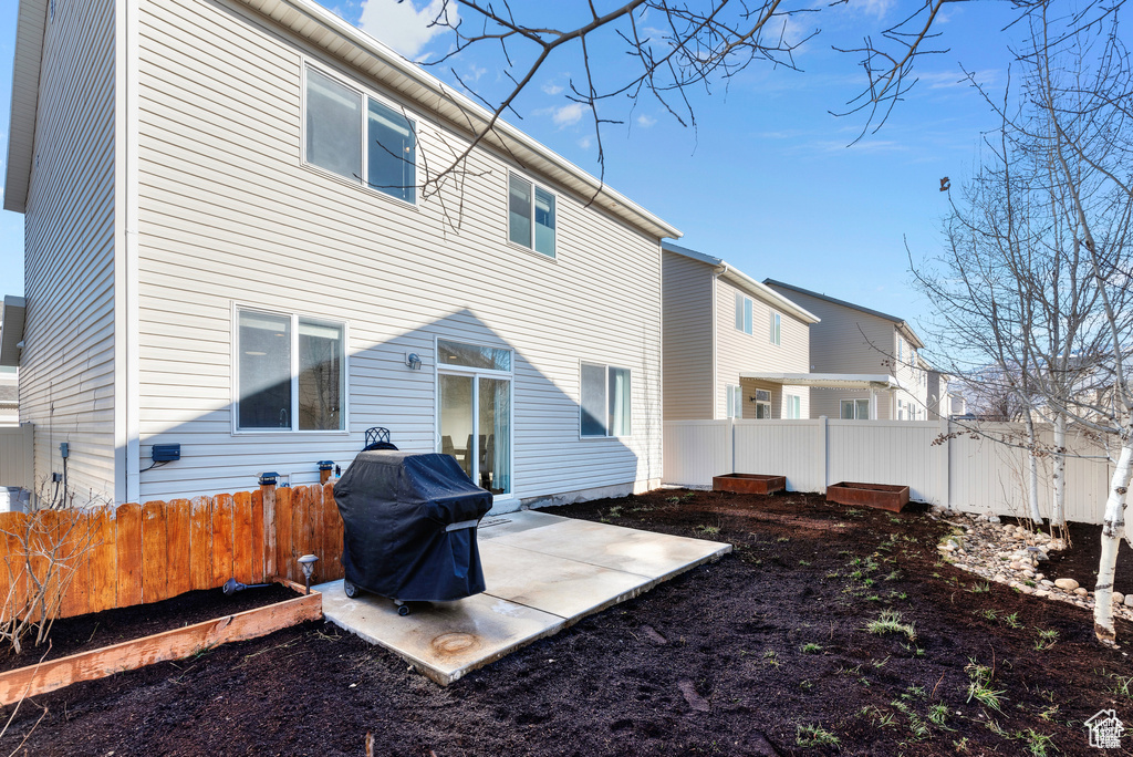 Back of house with a fenced backyard and a patio