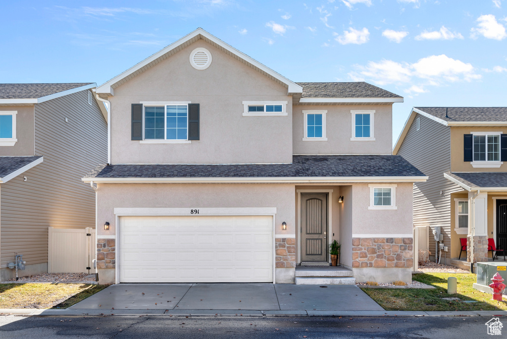 View of front of home with stone siding, stucco siding, and concrete driveway