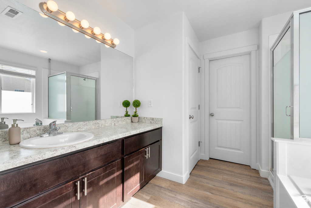 Bathroom featuring vanity, a shower stall, and wood finished floors