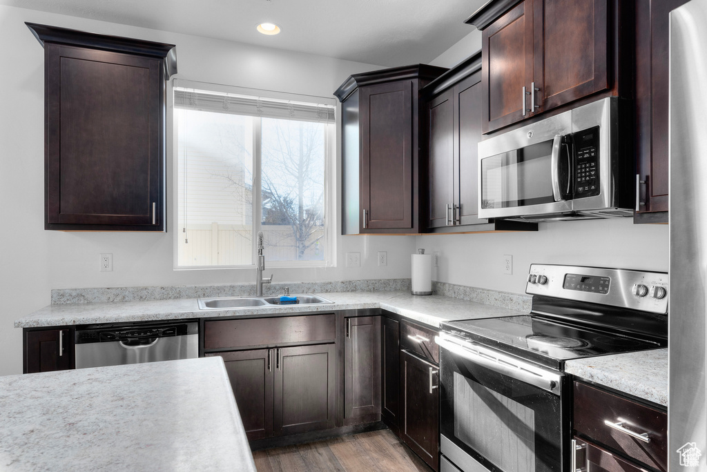 Kitchen with stainless steel appliances, light countertops, dark brown cabinets, and recessed lighting