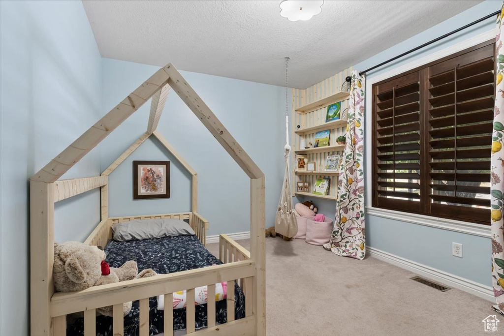 Carpeted bedroom with baseboards and a textured ceiling