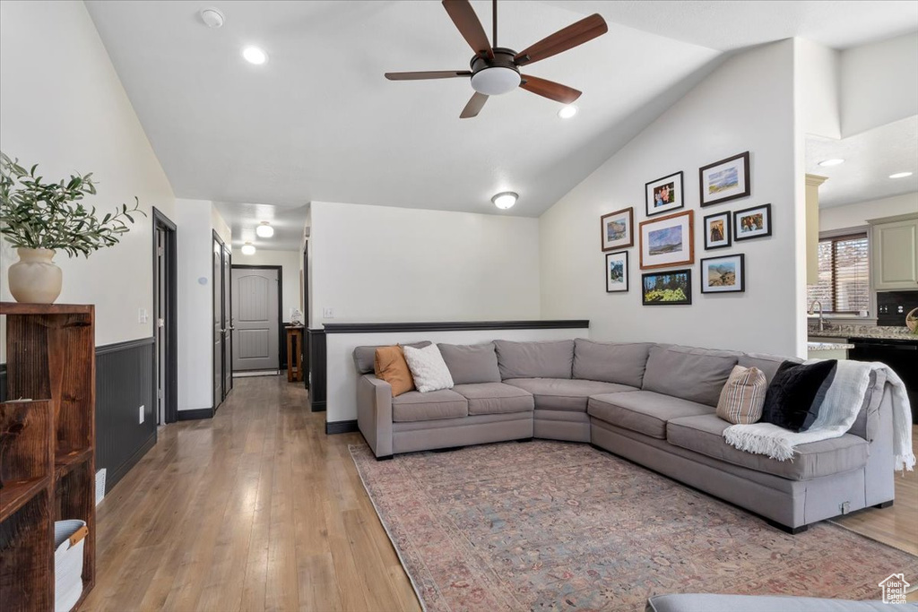 Living room with ceiling fan, vaulted ceiling, light wood-style floors, and recessed lighting