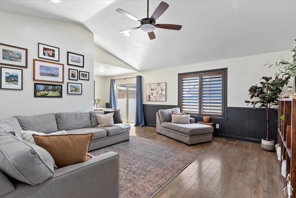 Living room featuring a wainscoted wall, ceiling fan, lofted ceiling, and hardwood / wood-style flooring