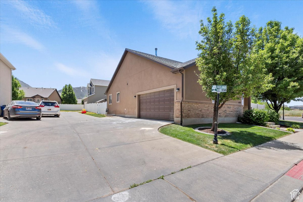 View of side of property featuring stucco siding, an attached garage, concrete driveway, and a residential view