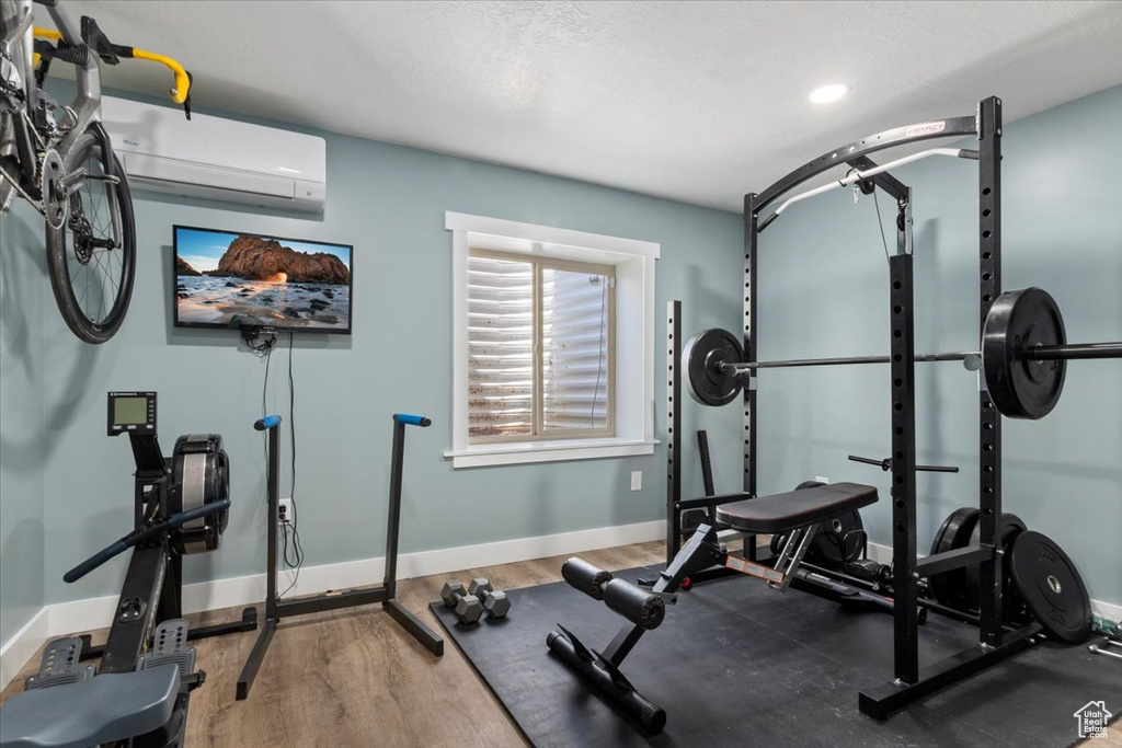 Exercise area featuring a wall mounted air conditioner and wood finished floors