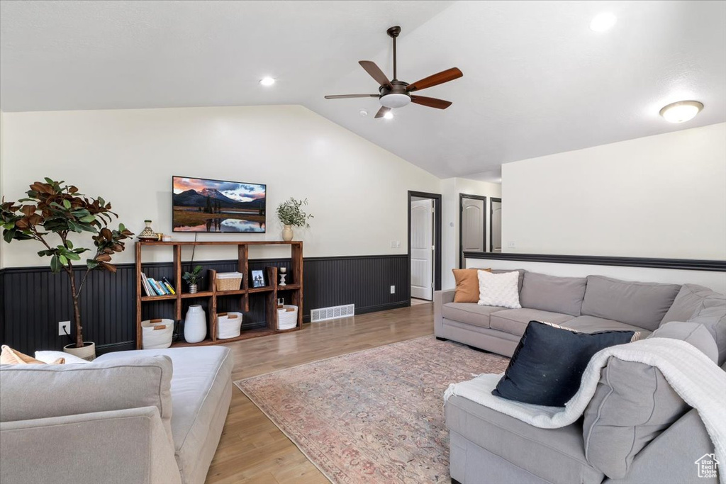 Living area with a wainscoted wall, ceiling fan, lofted ceiling, light wood-type flooring, and recessed lighting