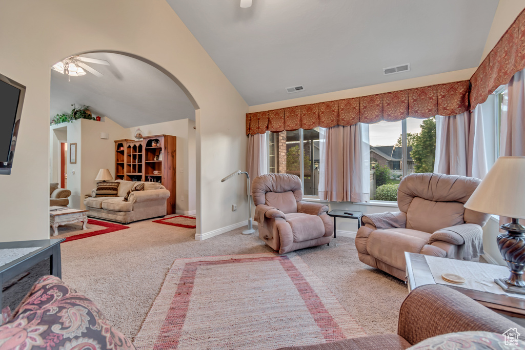 Living area featuring vaulted ceiling, ceiling fan, arched walkways, and carpet flooring