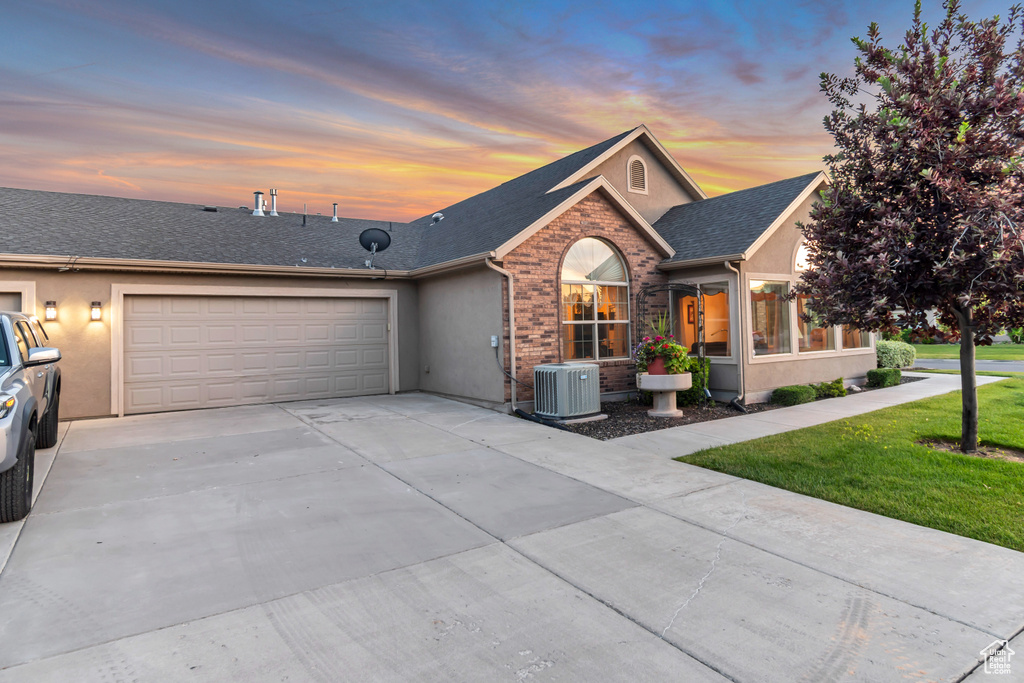 Ranch-style house with stucco siding, a garage, driveway, and a front yard