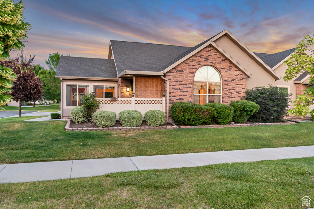 View of front of property featuring roof with shingles, brick siding, and a front yard
