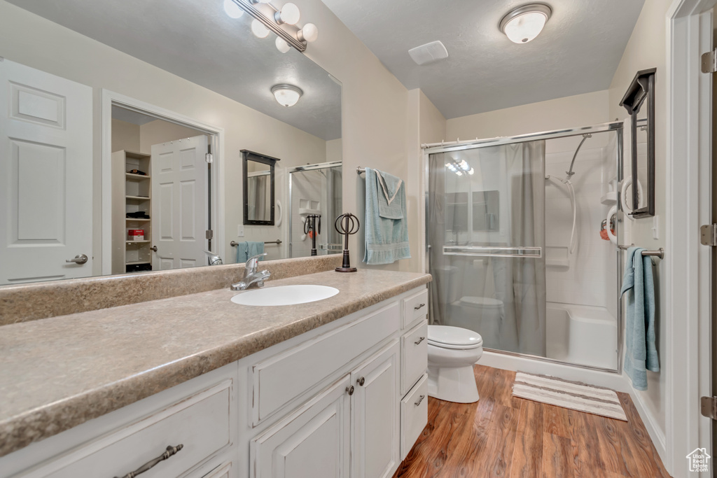 Full bathroom with vanity, a stall shower, and wood finished floors