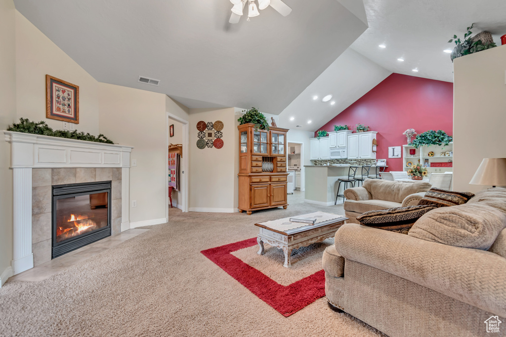 Living room with a ceiling fan, a fireplace, recessed lighting, light colored carpet, and vaulted ceiling