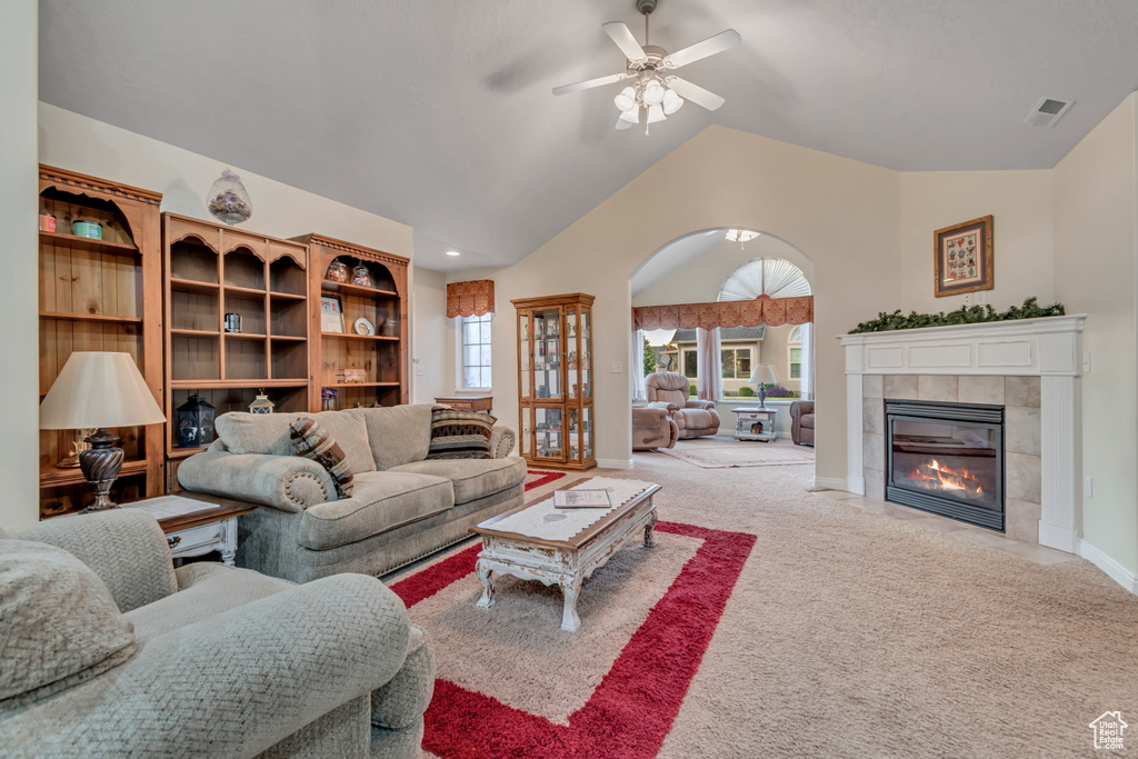 Living room with ceiling fan, light carpet, a fireplace, and high vaulted ceiling