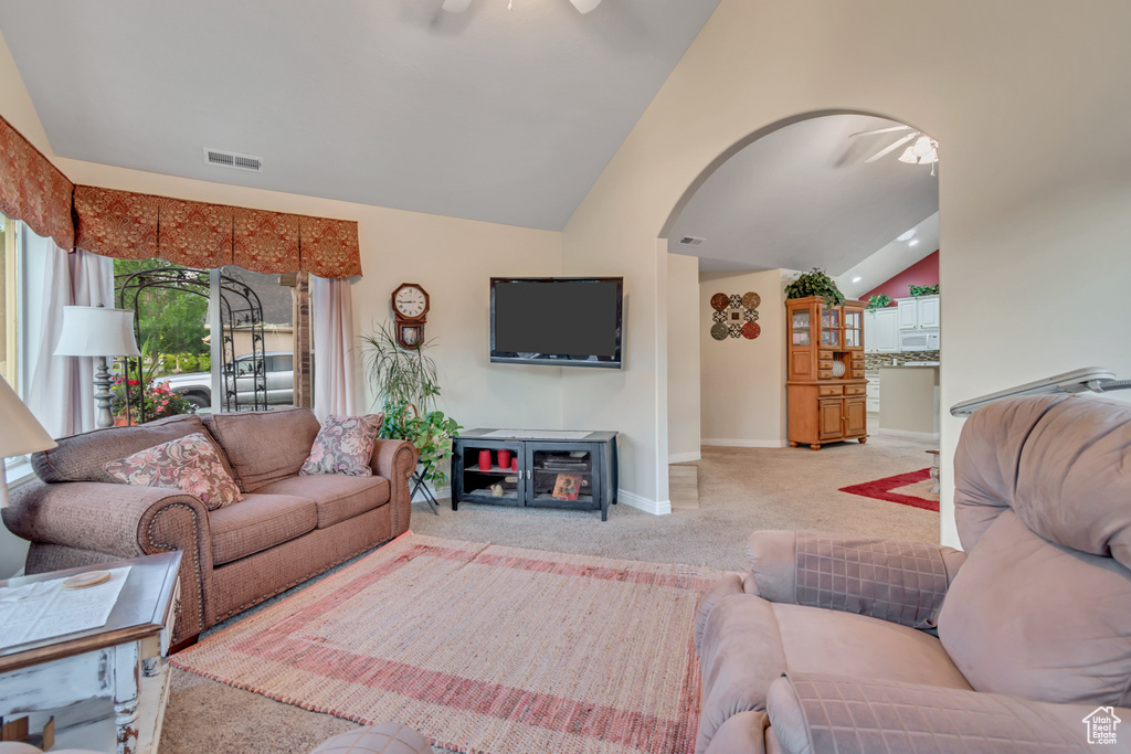 Carpeted living area with a ceiling fan, vaulted ceiling, and arched walkways