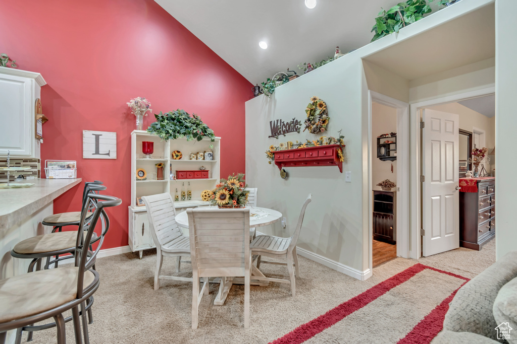 Dining room with light carpet, high vaulted ceiling, and recessed lighting