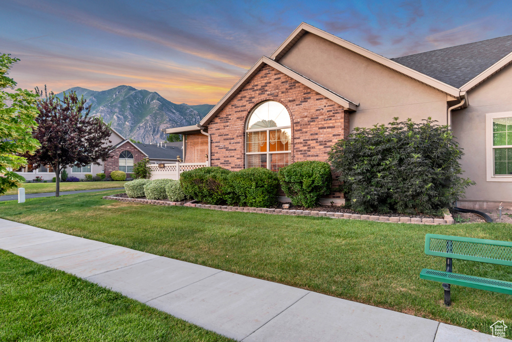 View of front of property featuring a lawn, brick siding, a mountain view, and stucco siding