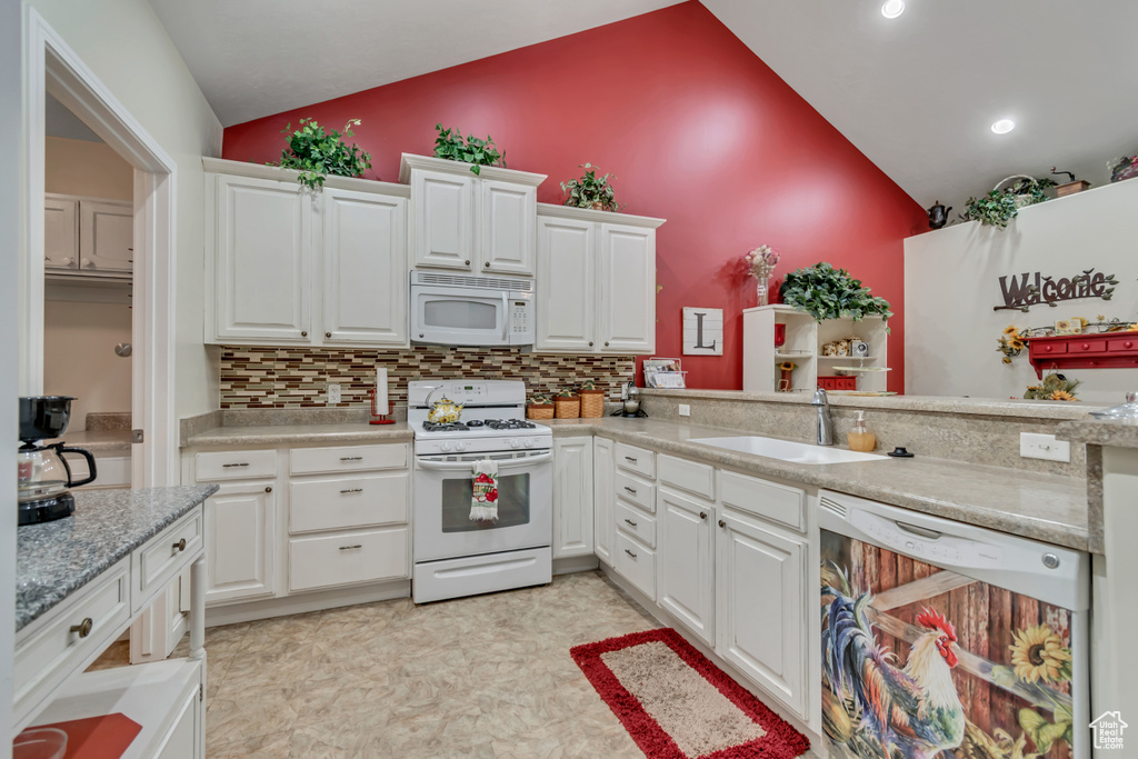 Kitchen with white appliances, tasteful backsplash, light countertops, white cabinets, and recessed lighting