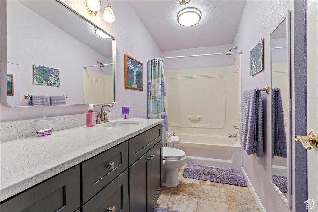 Bathroom with vanity, shower / tub combo with curtain, and stone finish flooring