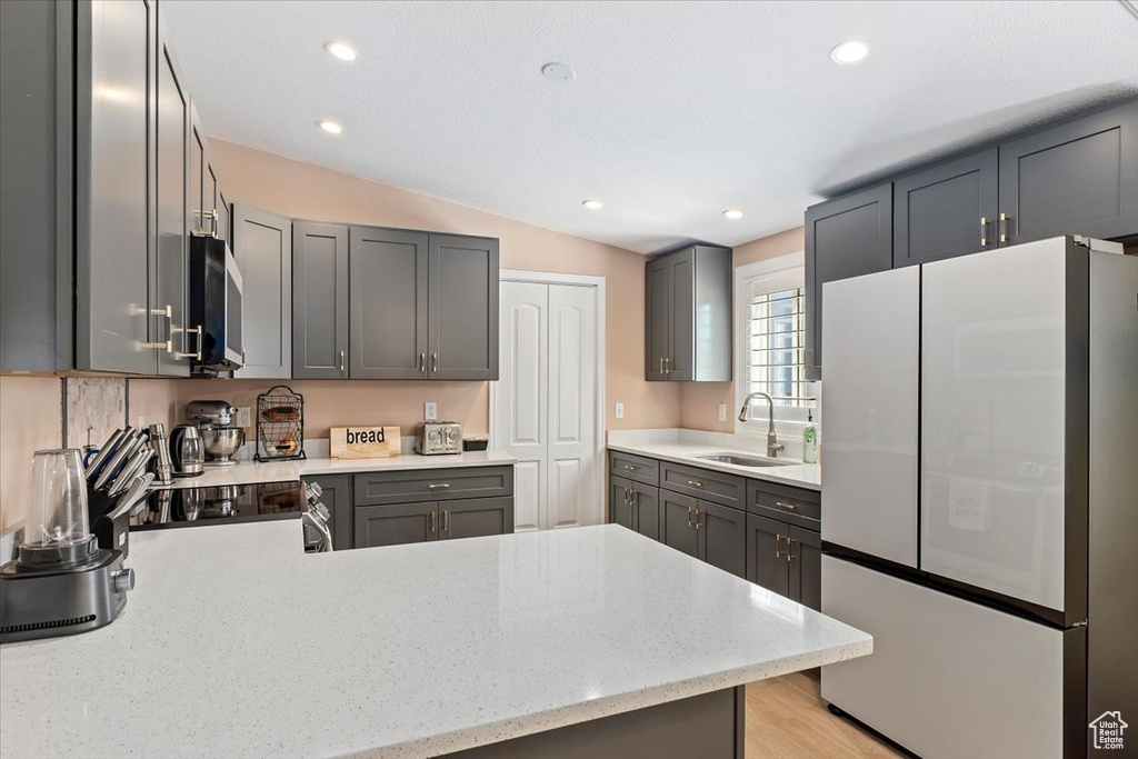 Kitchen featuring freestanding refrigerator, stainless steel microwave, a peninsula, recessed lighting, and vaulted ceiling