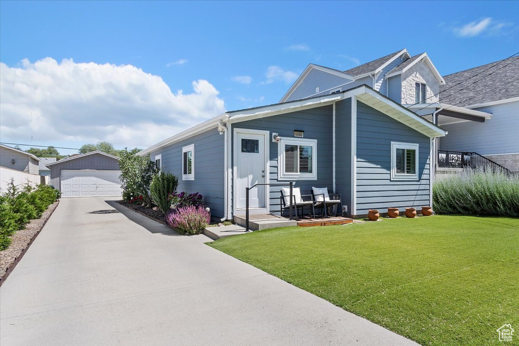 View of front of home featuring an outbuilding, a garage, and a front lawn