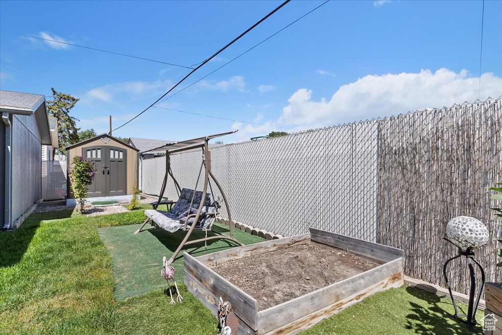 Fenced backyard featuring a storage shed and a garden