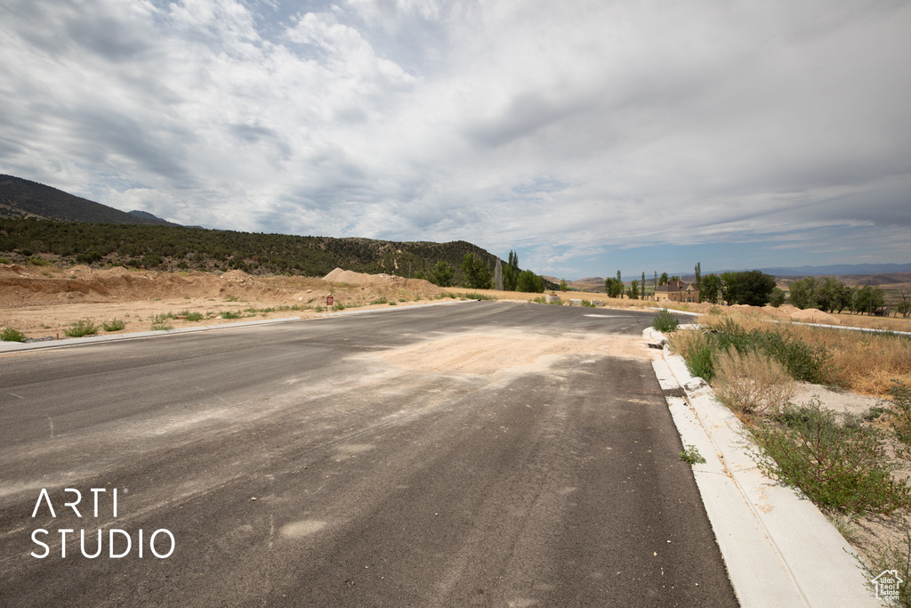 View of asphalt road featuring curbs and a mountain view