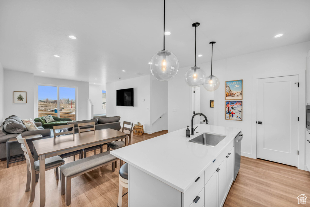 Kitchen featuring open floor plan, light wood-style flooring, recessed lighting, white cabinetry, and dishwasher