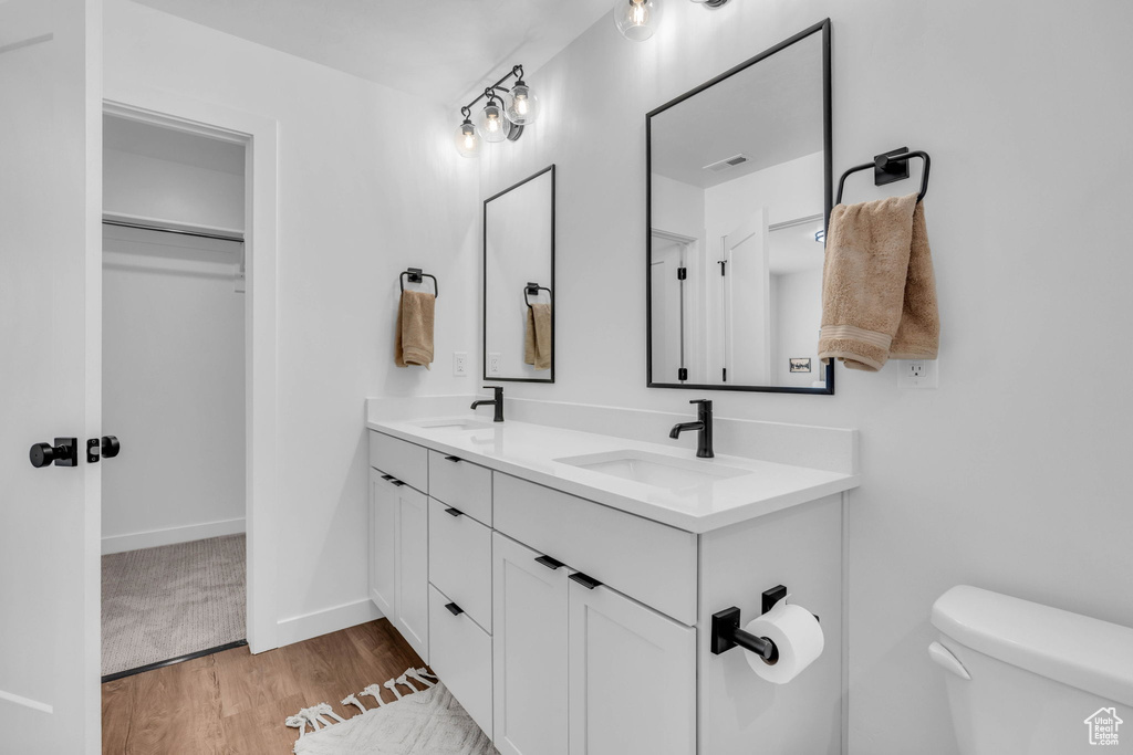Full bath featuring double vanity, wood finished floors, and a walk in closet