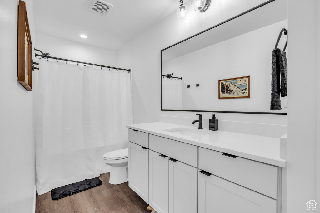 Bathroom featuring vanity, wood finished floors, shower / tub combo, and recessed lighting
