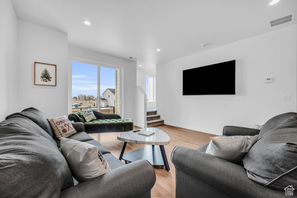 Living room with stairway, light wood-style floors, and recessed lighting