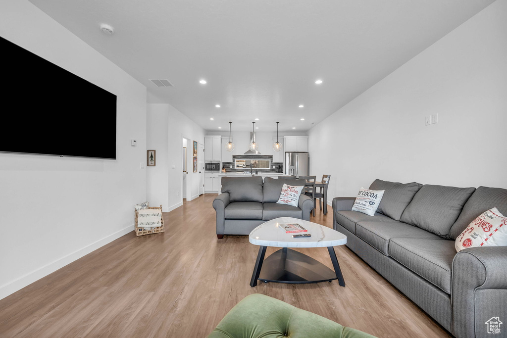 Living area with light wood-type flooring and recessed lighting