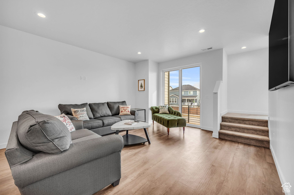 Living room featuring light wood-style flooring, stairs, and recessed lighting