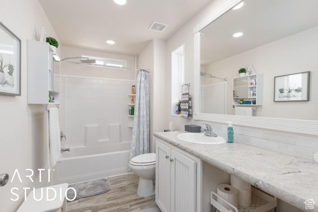 Bathroom with wood finished floors, vanity, shower / bath combo with shower curtain, and recessed lighting