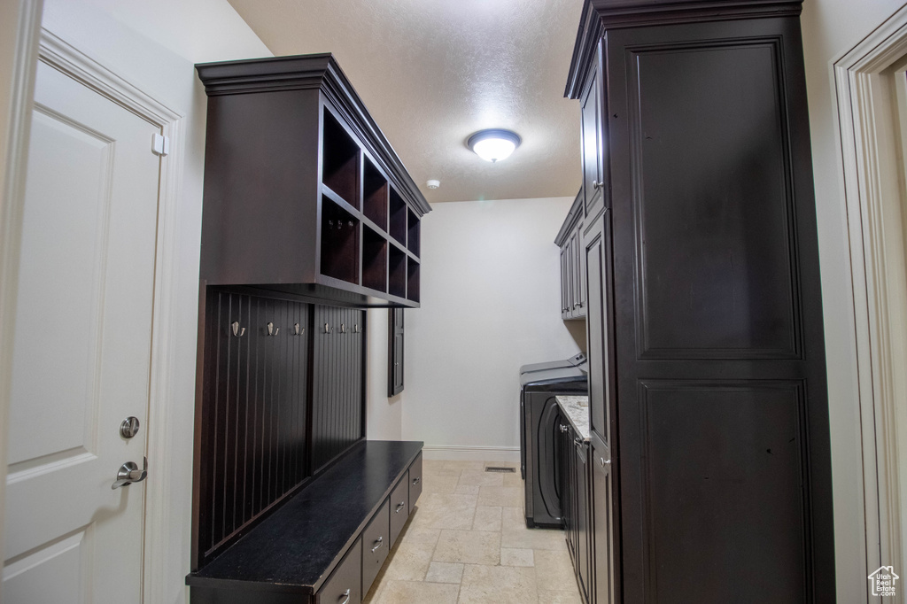 Laundry room featuring stone tile flooring, cabinet space, and washer / clothes dryer