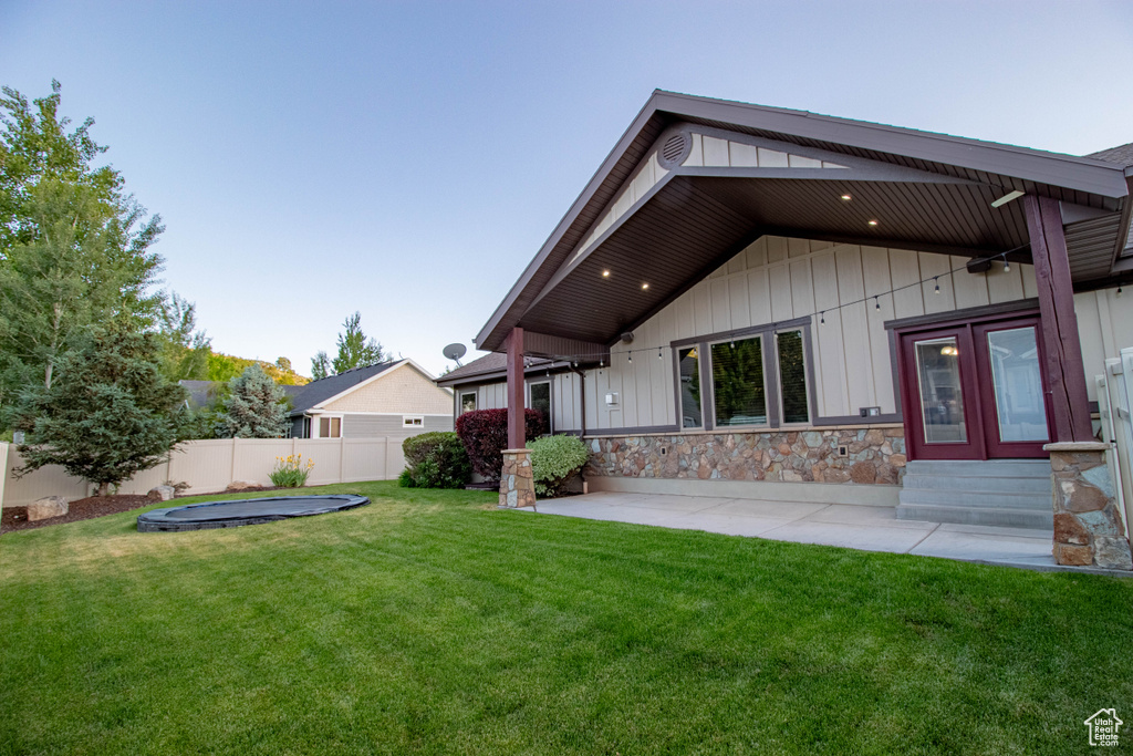 Rear view of house featuring entry steps, a patio area, stone siding, and french doors