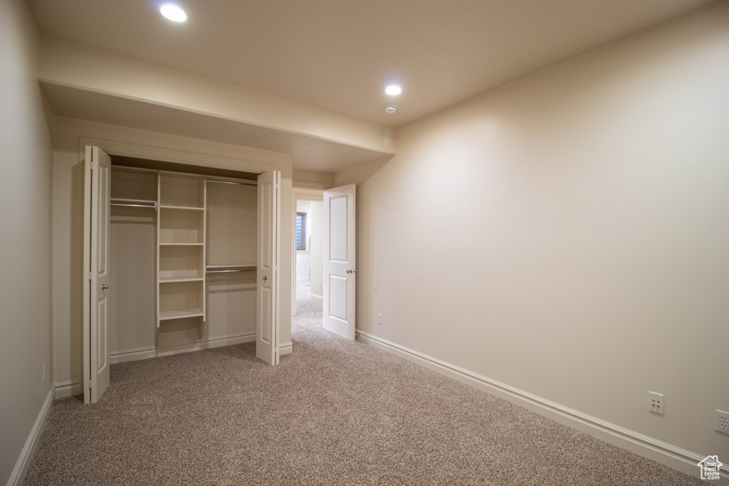 Unfurnished bedroom featuring light carpet, a closet, and recessed lighting