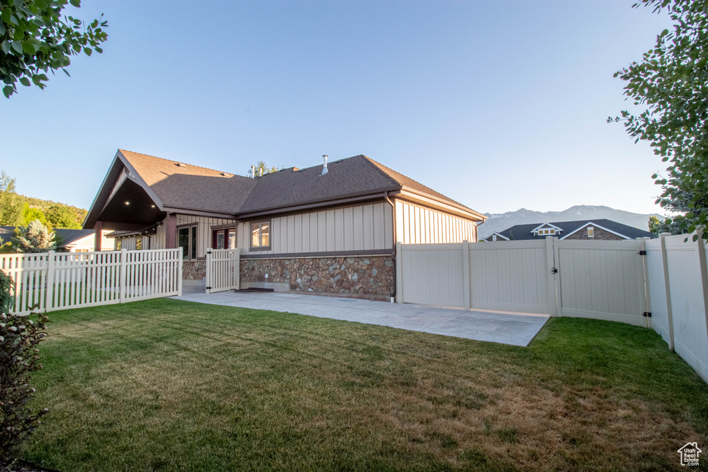 Back of house with a gate, a patio area, a fenced backyard, and stone siding