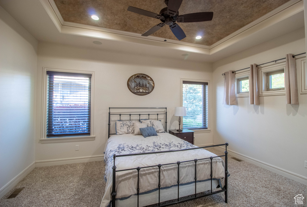 Carpeted bedroom featuring a tray ceiling, crown molding, recessed lighting, and ceiling fan