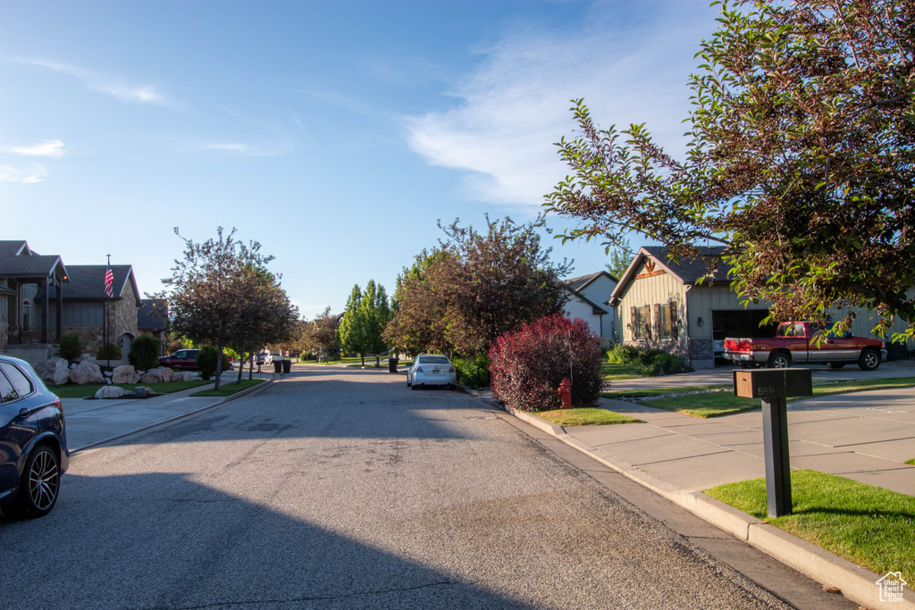 View of asphalt road featuring curbs, a residential view, and sidewalks
