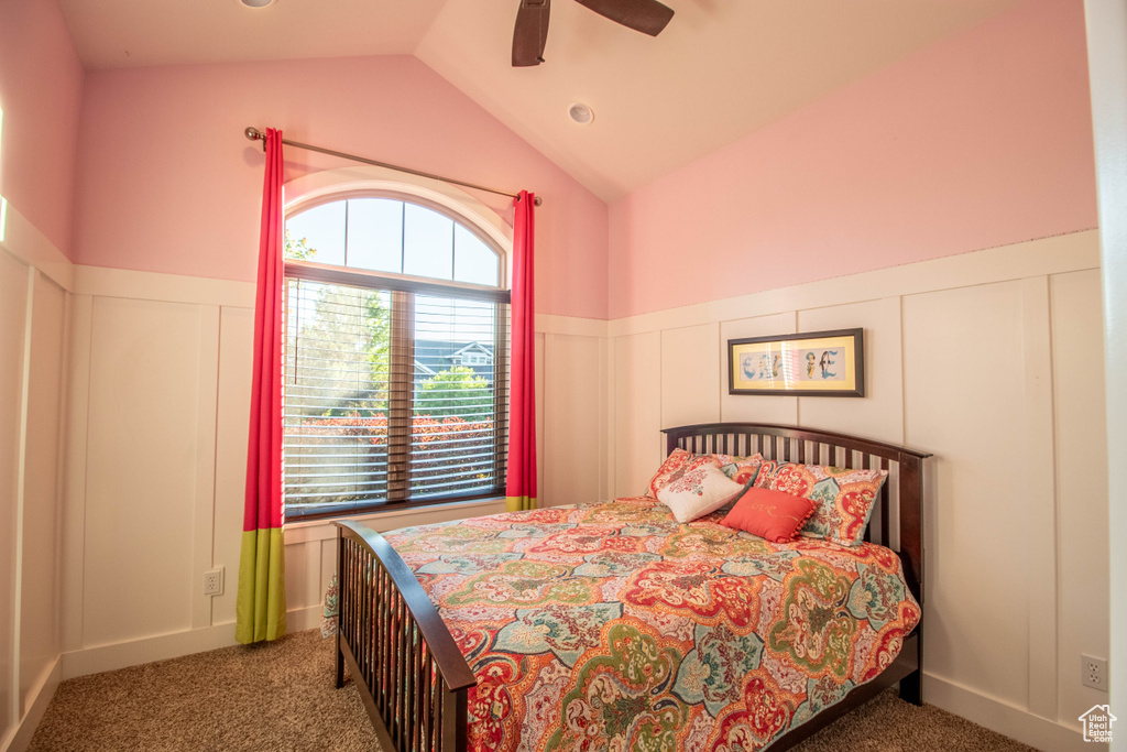 Bedroom with a decorative wall, carpet flooring, a wainscoted wall, lofted ceiling, and ceiling fan