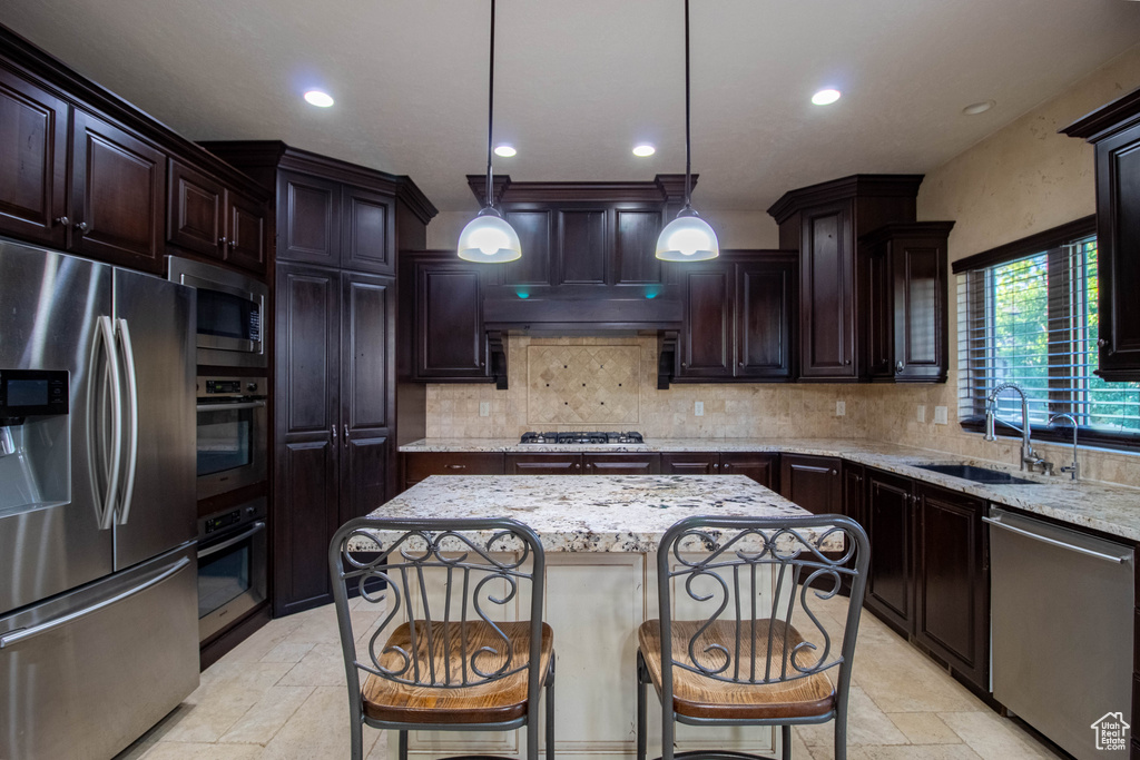 Kitchen with stainless steel appliances, stone tile flooring, recessed lighting, a center island, and light stone countertops
