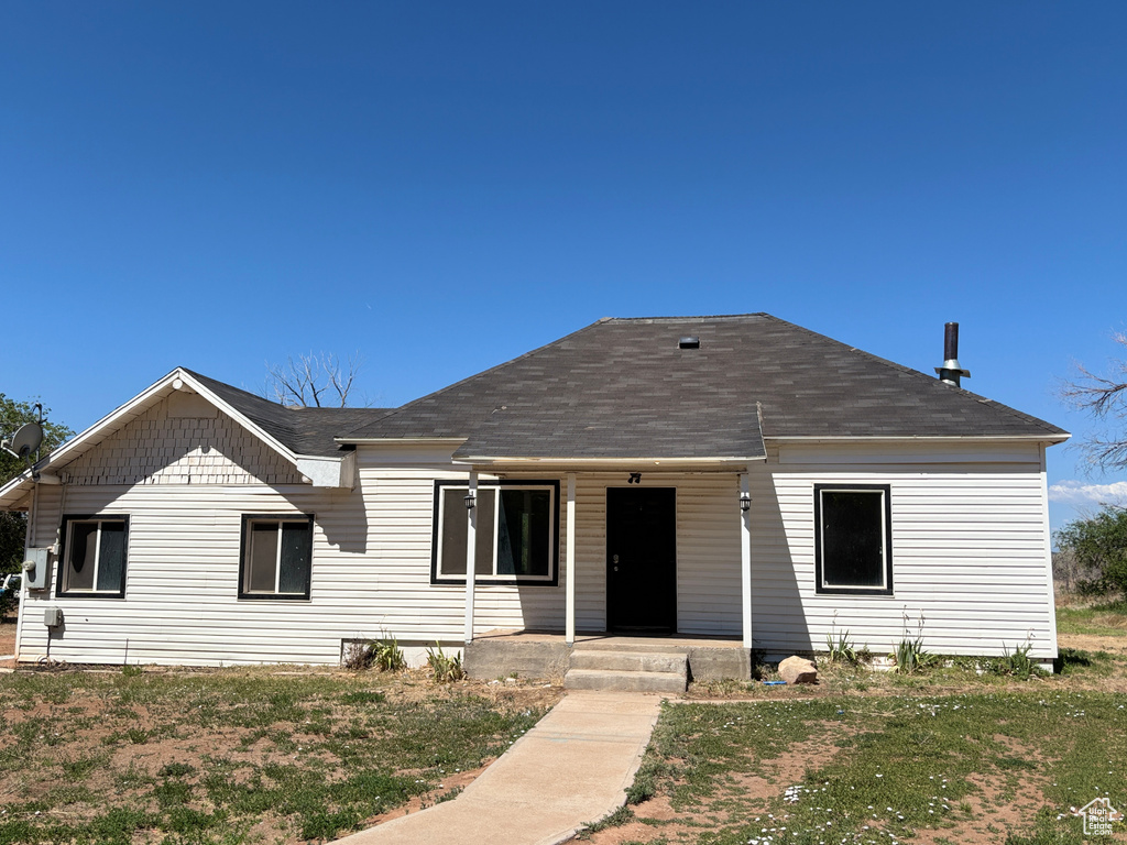 View of front of home featuring a shingled roof, covered porch, and a front yard