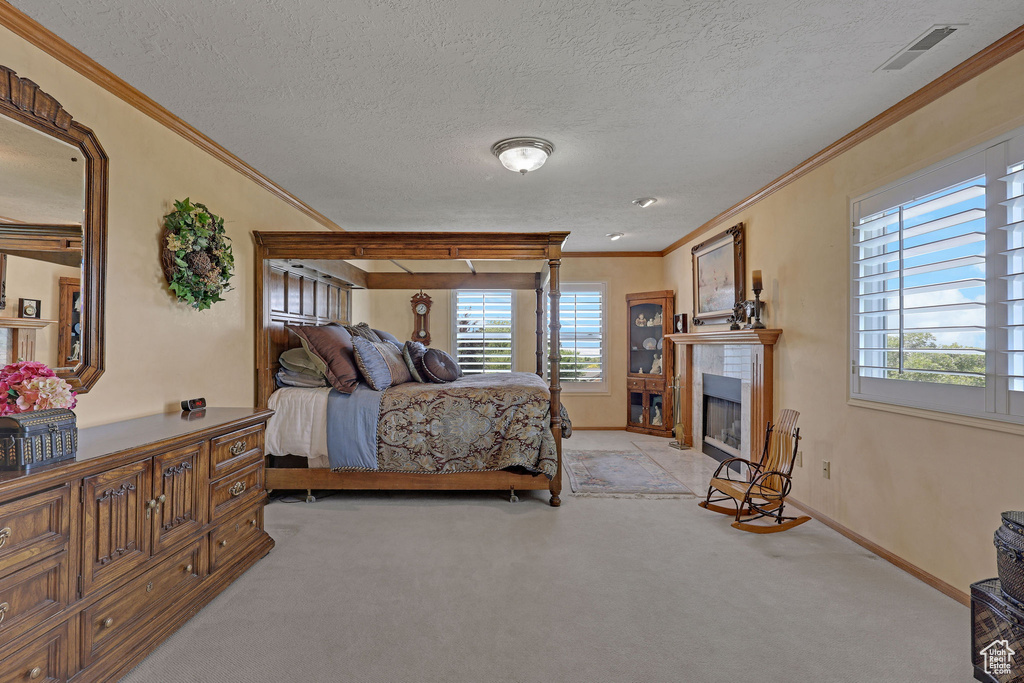 Bedroom with crown molding, multiple windows, light colored carpet, a fireplace with flush hearth, and a textured ceiling