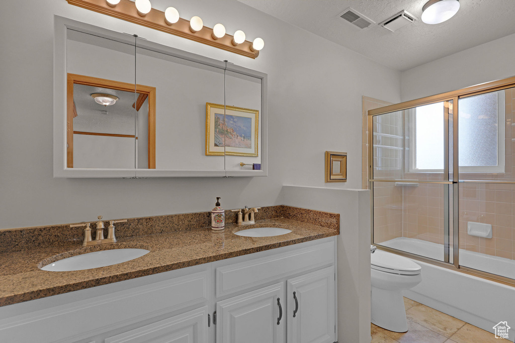 Bathroom featuring double vanity, combined bath / shower with glass door, and tile patterned flooring