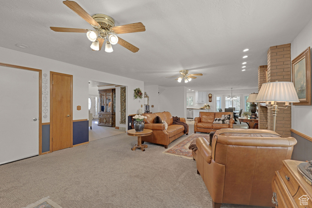 Living area with a ceiling fan, light carpet, and a chandelier