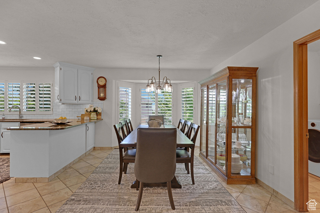 Dining area with a chandelier, light tile patterned floors, recessed lighting, and a textured ceiling